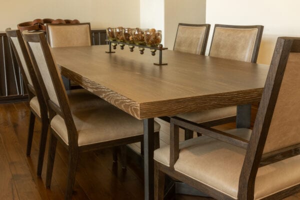 View of a dining area with table, chairs, and centerpiece of various pine cones in glass containers.