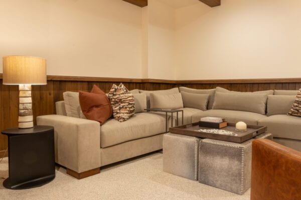 View of of sectional couch with ottomans topped with a large tray containing puzzle pieces, books, and a candle.