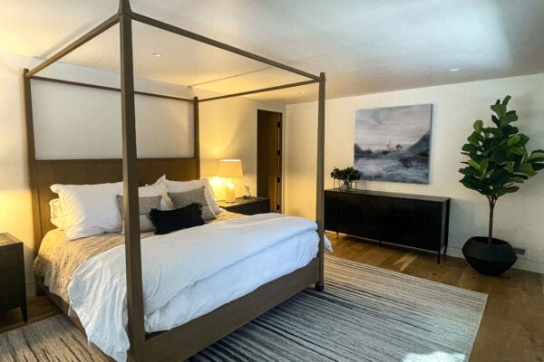 View of a bedroom with four-post bed, dresser, large rug and tree